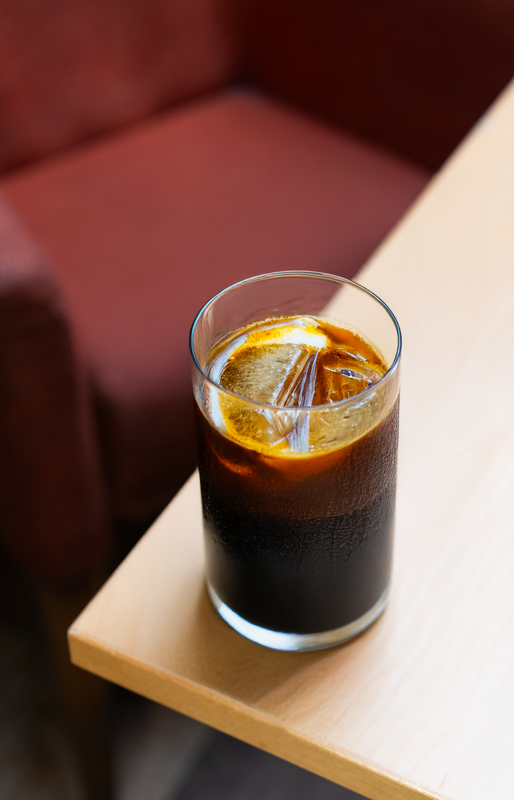 Glass of an espresso tonic on the edge of a table. 