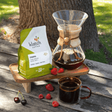 Klatch Coffee package with a Chemex coffee maker and a cup of coffee on a wooden surface outdoors.