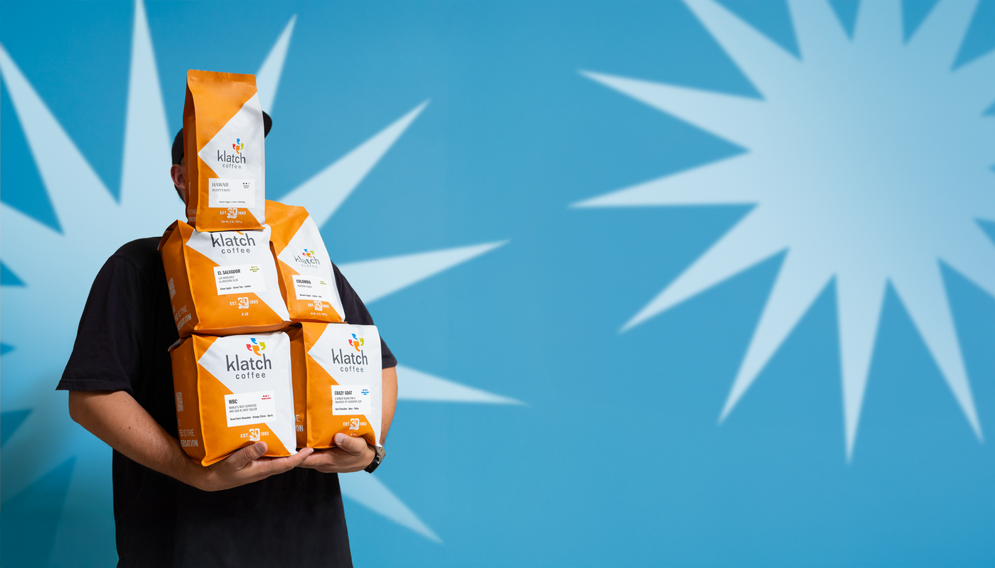 Man holding orange 2 and 5 pound bags of coffee, set against a blue background with white starbursts.