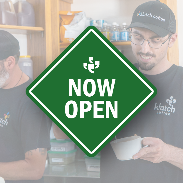 Klatch Coffee team members preparing coffee behind a green “Now Open” graphic.