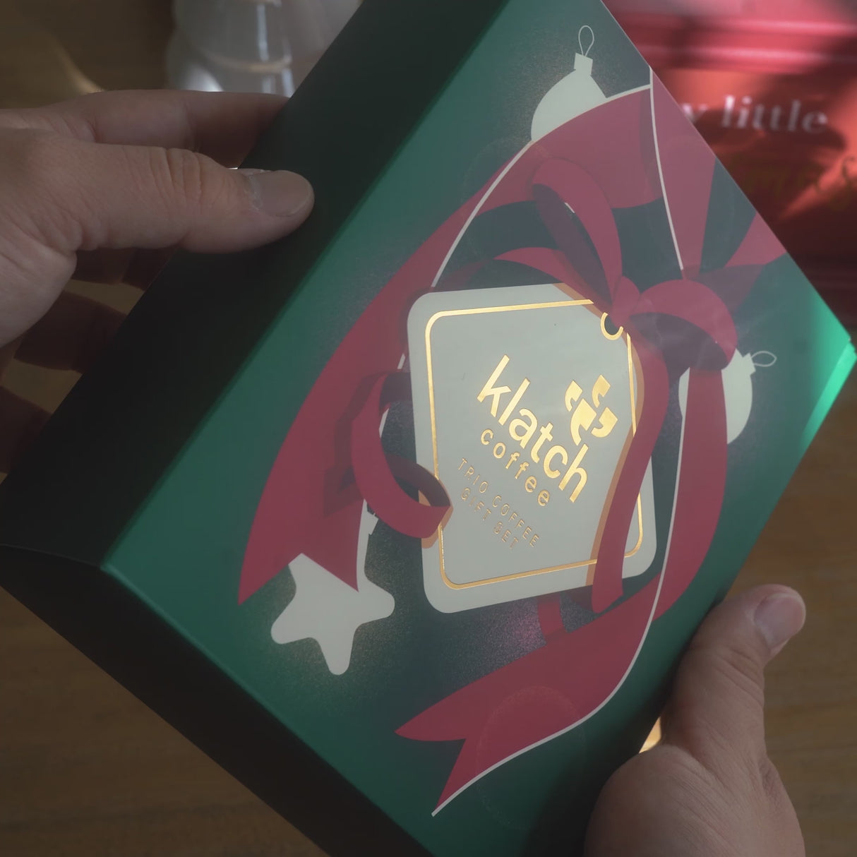 A man opens a coffee trio gift set, selects a bag, and brews it using a Chemex. He slowly pours the finished coffee into a mug on the counter.