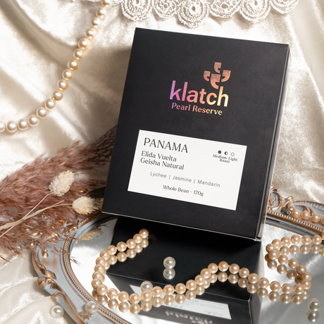 Klatch Pearl Reserve box on top of a mirror with pearls, velvet white background with lace and a string of pearls.