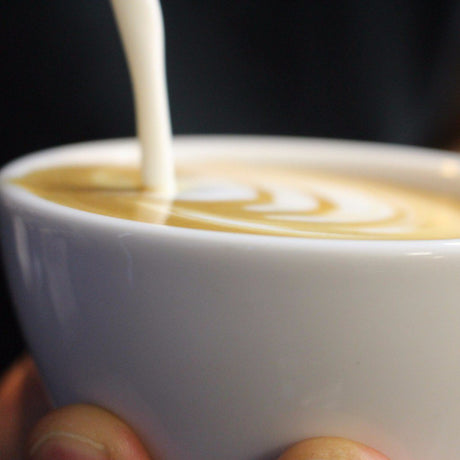 Pouring milk into a mug, creating latte art