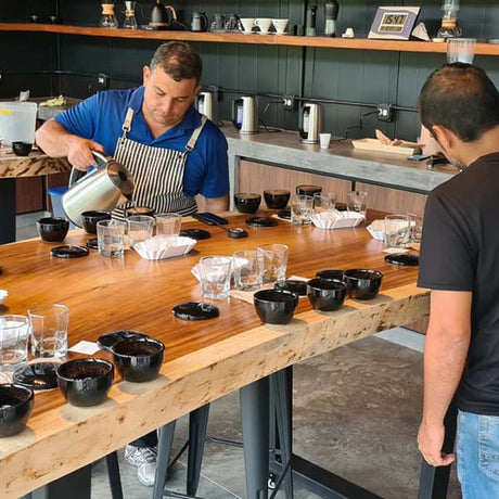Altieri  Estate cupping coffee lab with 2 men setting up cupping table.